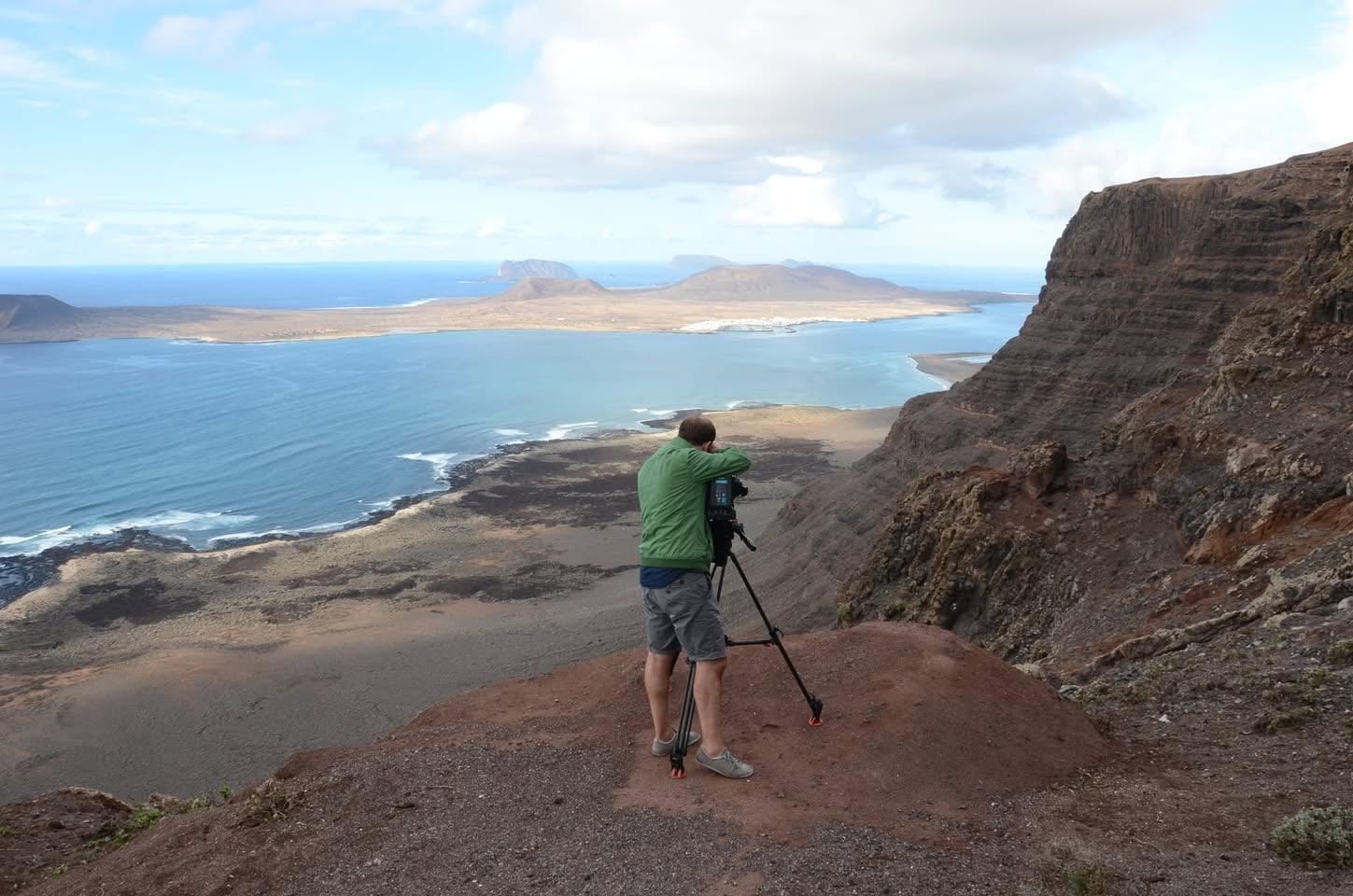 Cameraman with tripod on a cliff above the sea